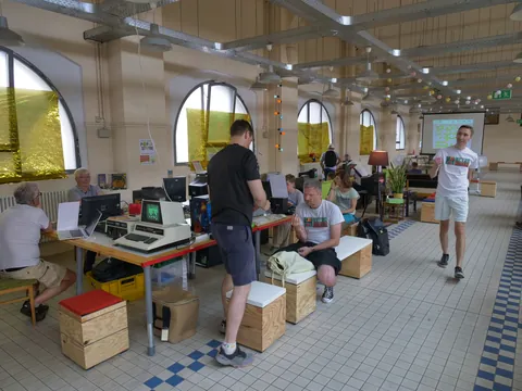 Teilnehmer arbeiten an Computern in einem hellen, offenen Workshop-Raum mit hohen Decken.