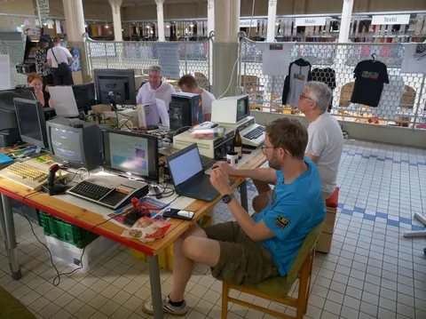 Mehrere Enthusiasten testen vintage Computer und Retro-Hardware bei einer Ausstellung in einer Halle.