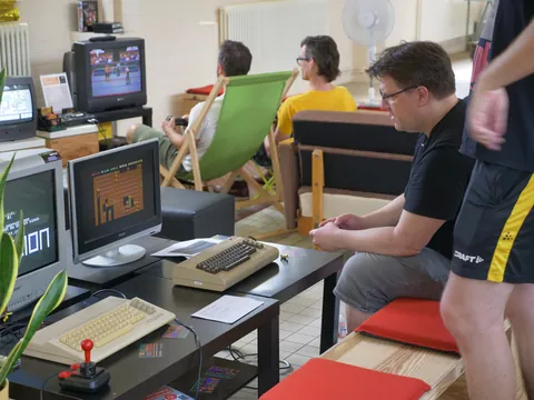 Gruppe spielt Retro-Videospiele auf alten Computern mit CRT-Monitoren in einem Raum.