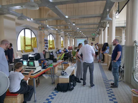 Menschen bei einer Retro-Computer-Ausstellung in einer großen Halle mit historischer Architektur.