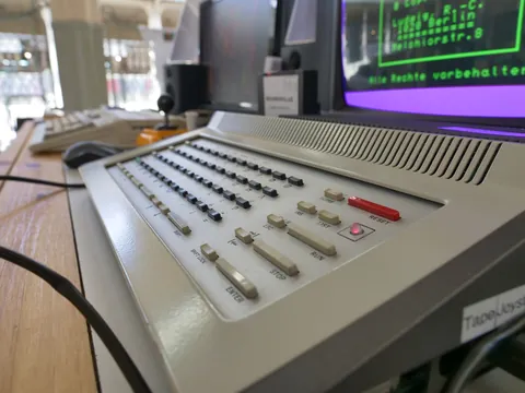 Alter Computer-Terminal mit Tastatur, rotem Reset-Taste und grünem Text-Monitor im Hintergrund.