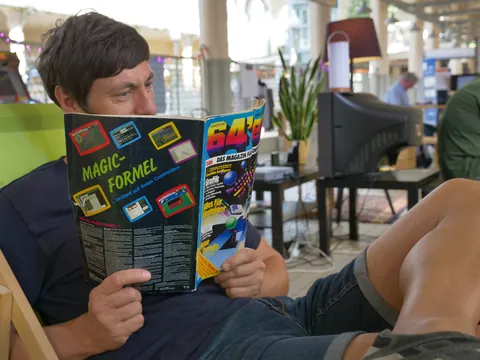 Mann liest das 64'er Computer-Magazin mit dem Cover-Thema Magic-Formel.