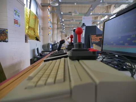 Vintage-Computer mit rotem Joystick, Tastatur und Monitor in einer Ausstellung.