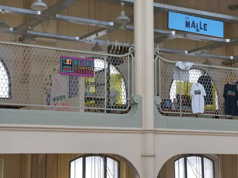 Innenansicht mit Retro Computer Dresden, Die Malle Schild und T-Shirts am Geländer.