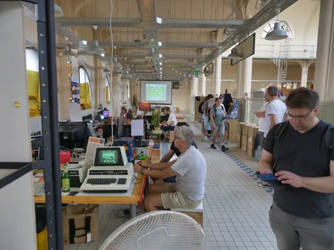 Menschen nutzen alte Computer in einer großen Industriehalle bei einem Retro-Computing-Event.