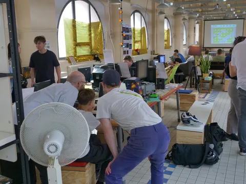 Teilnehmer eines Workshops arbeiten an Computern in einem Raum mit Bogenfenstern und Beamer.