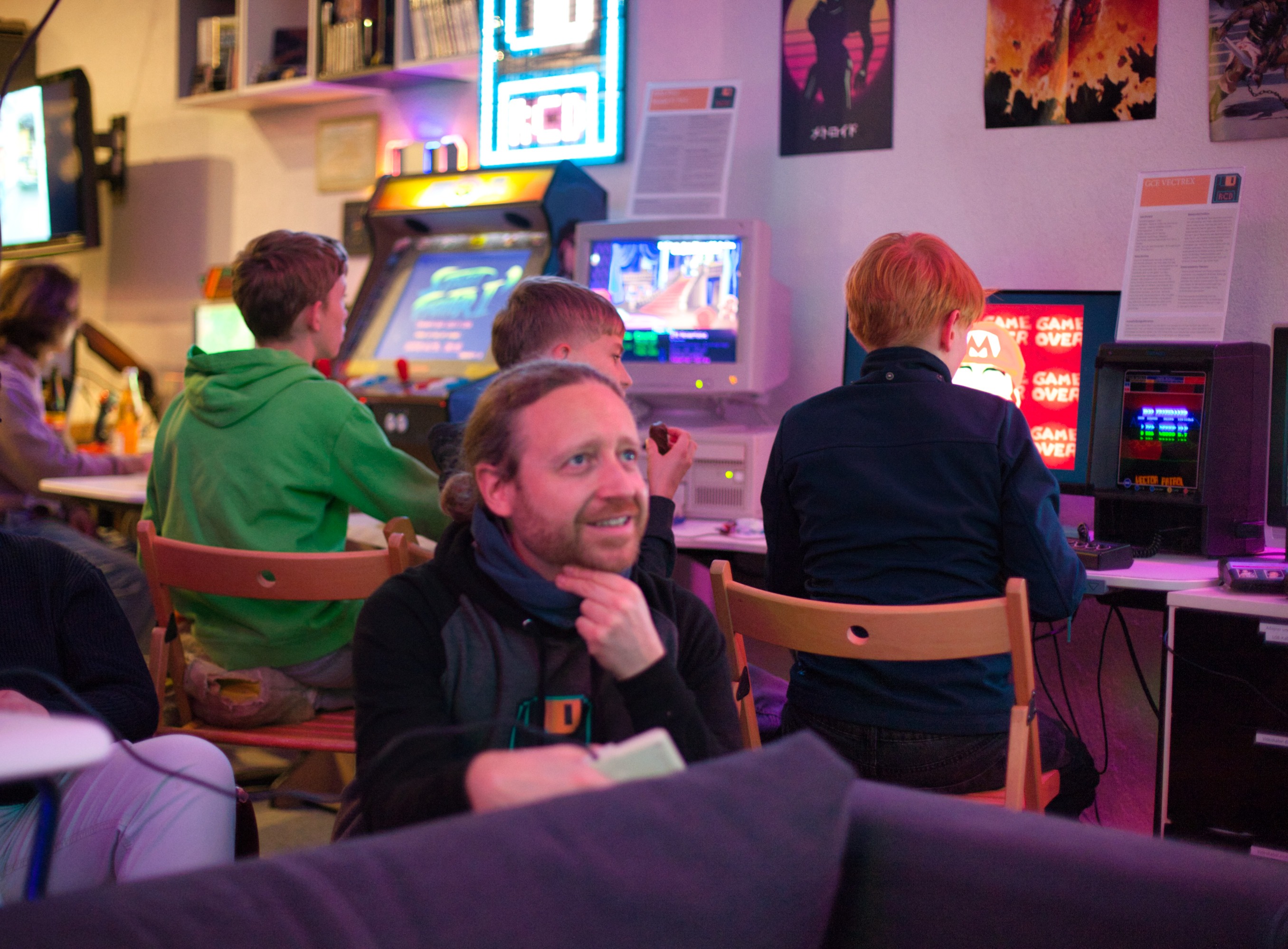 Lächelnde Person im Vordergrund und im Hintegrund Arcade Automat