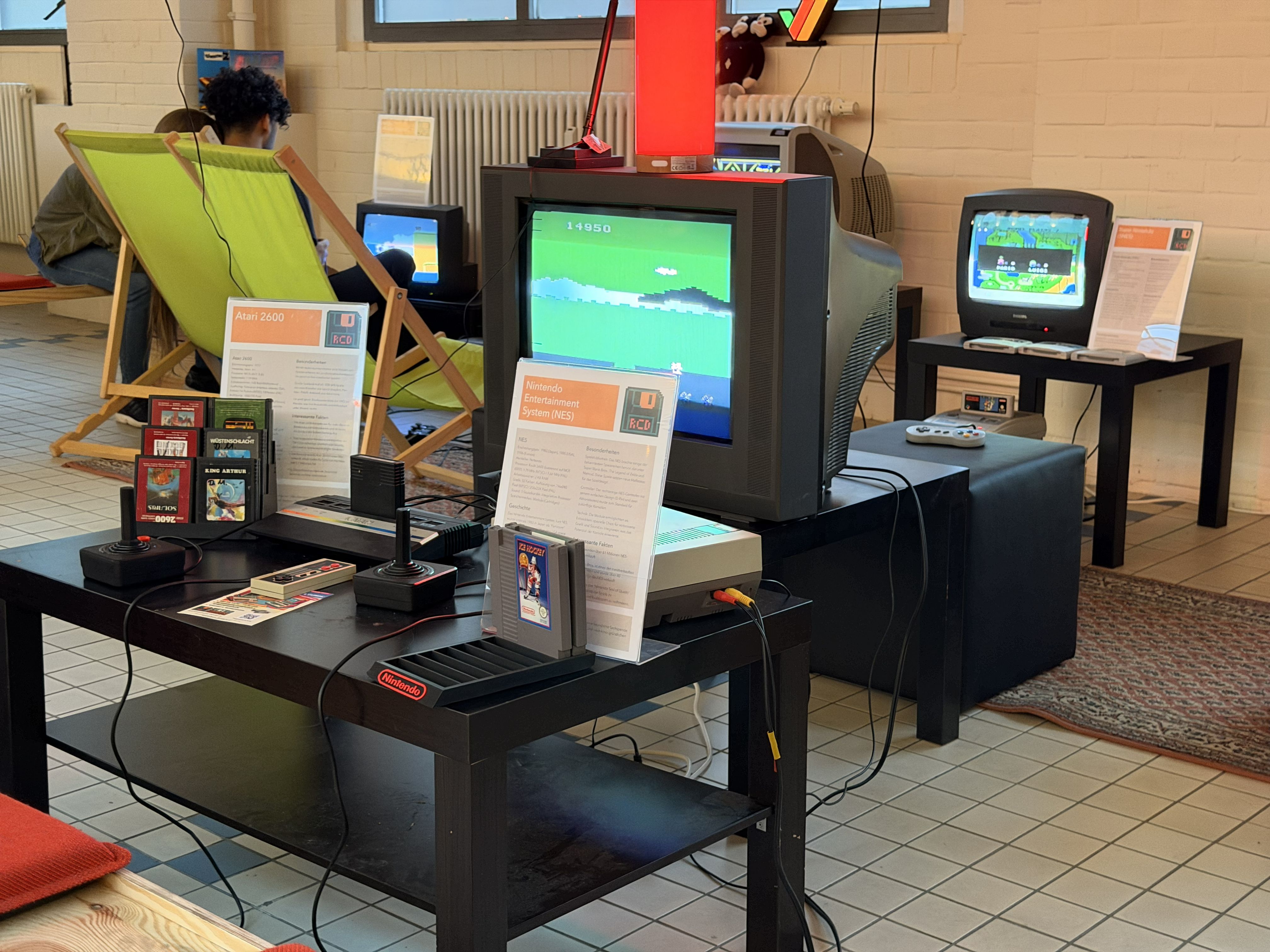 Ausstellungstisch mit Atari 2600 und NES samt Infotafeln und Modulsammlung