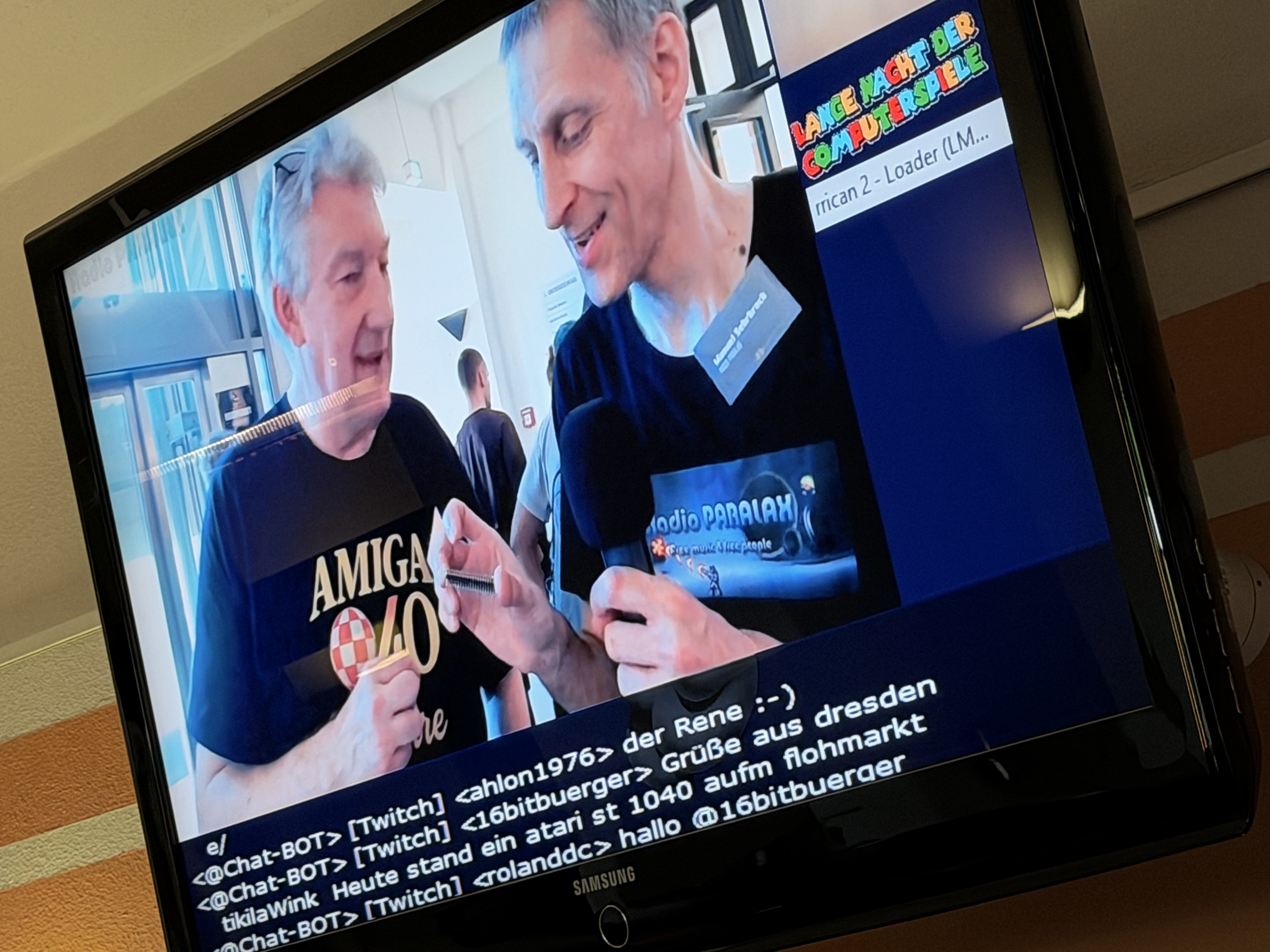 Ein großer Monitor auf dem eine Interviersituation auf Twitch zwischen Vegatronic und PARALAX zu sehen ist