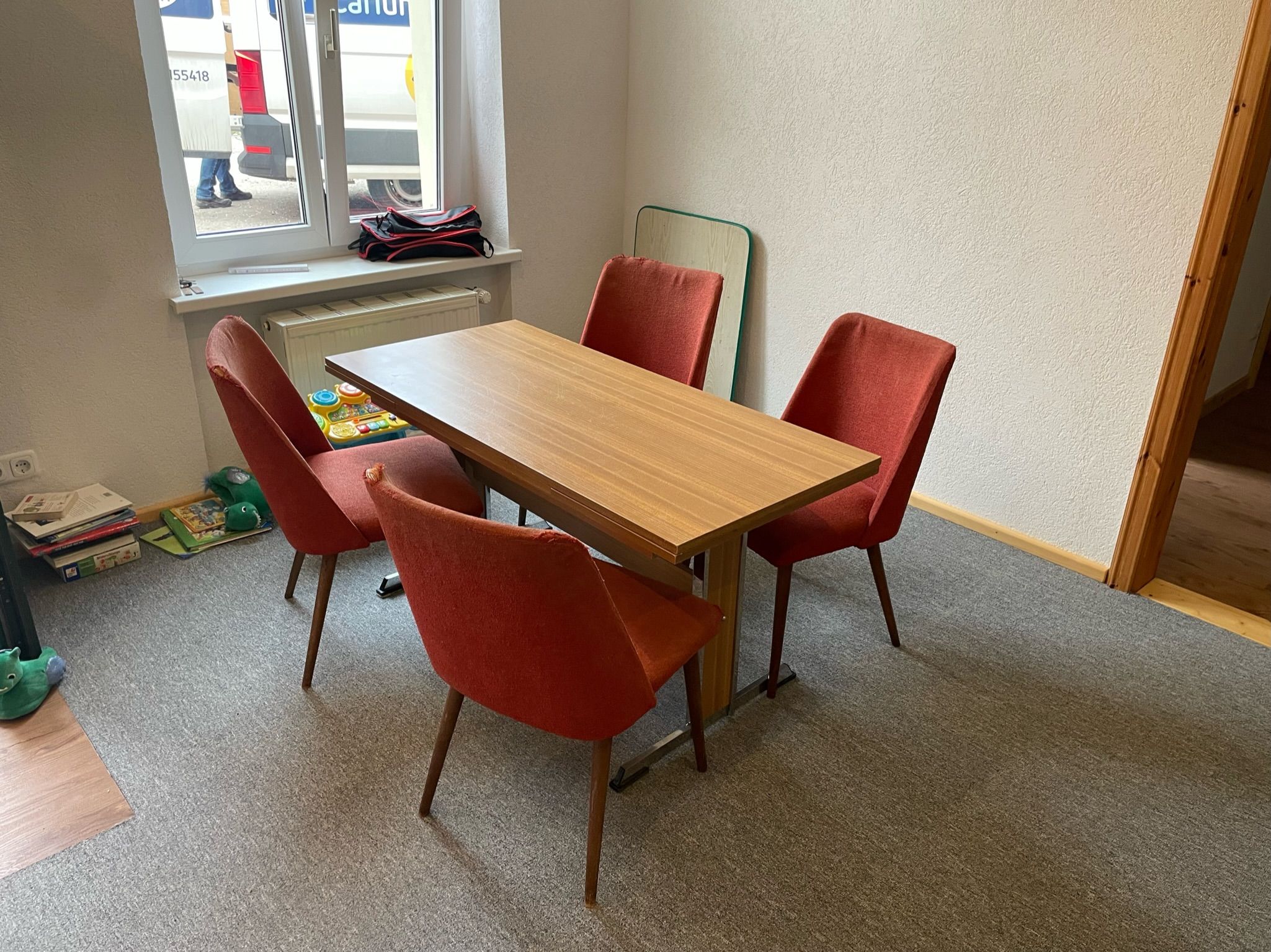 Ein ausziehbarer DDR-Tisch mit vier Stühlen in einem weitgehend leeren Raum